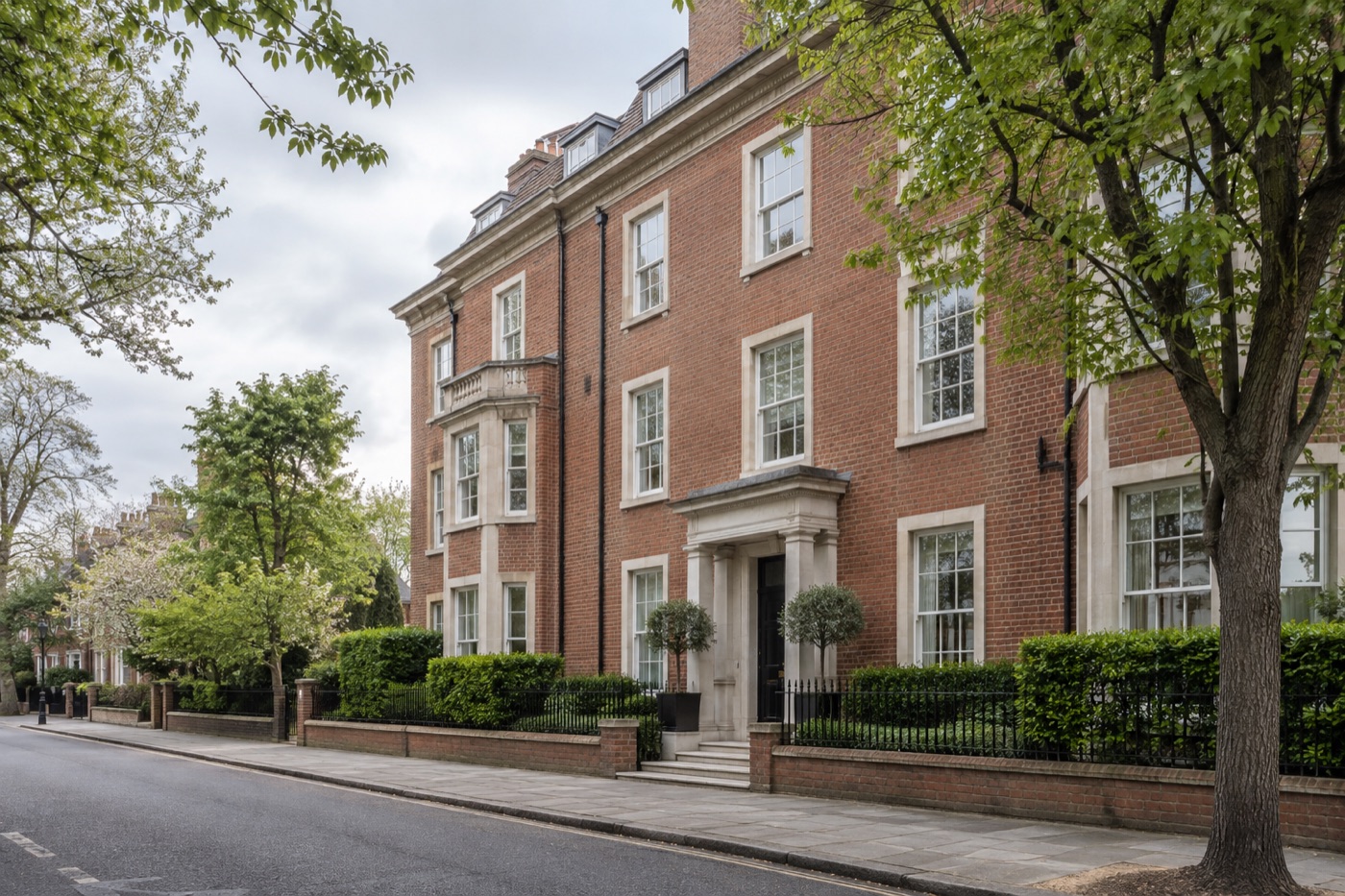 Red-brick residential apartment building on a tree-lined English street
